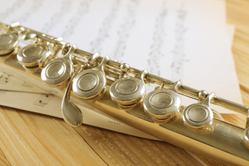 Naklejka premium Silver flute with music notes on wooden table close up