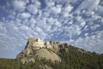 White puffy clouds behind Presidents George Washington, Thomas Jefferson, Teddy Roosevelt and Abraham Lincoln at Mount Rushmore National Memorial, South Dakota