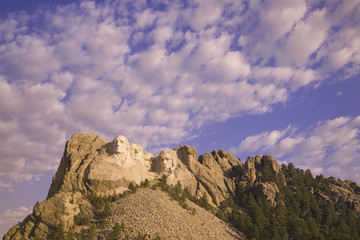 White puffy clouds behind Presidents George Washington, Thomas Jefferson, Teddy Roosevelt and Abraham Lincoln at Mount Rushmore National Memorial, South Dakota