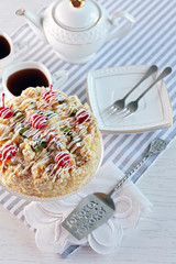 Butter cake with cherries on stand and table setting, on light background