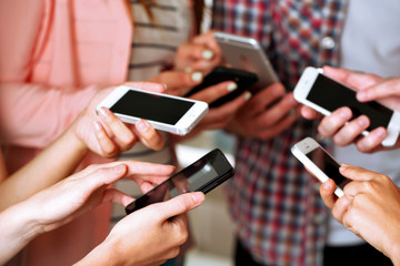 Many hands holding mobile phones close up