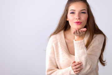  Young woman giving an air kiss, isolated on white background