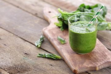 Glass of spinach juice on wooden background