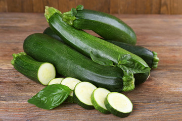 Fresh zucchini with basil on wooden table close up