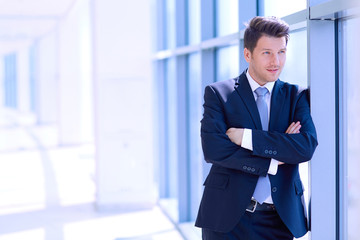 Fototapeta premium Portrait of businessman standing near window in office