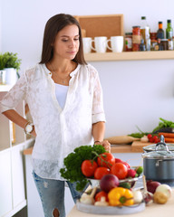 Young woman standing by the stove in the kitchen
