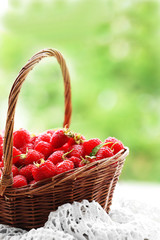 Fototapeta na wymiar Fresh raspberries in wicker basket on wooden table on blurred nature background