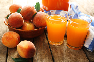 Ripe peaches and juice in glass on wooden background