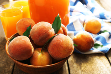 Ripe peaches and juice in glass on wooden background