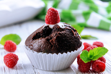 Delicious chocolate cupcake with berries on wooden table close up