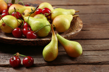 Ripe pears and cherries on wooden table close up