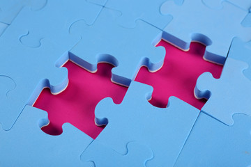Missing puzzle pieces on pink surface, closeup