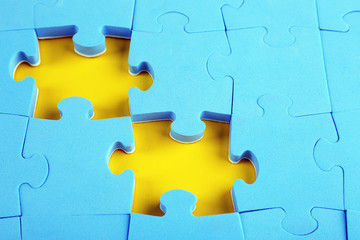 Missing puzzle pieces on yellow surface, closeup