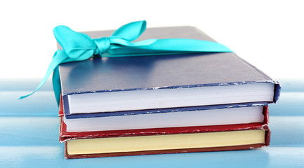 Stack of books with ribbon on table isolated on white