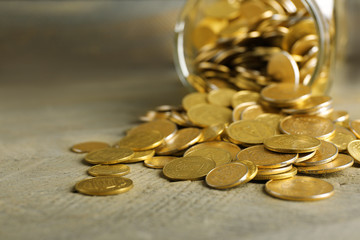 Glass jar with coins on wooden background