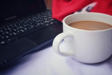 Computer notebook with coffee cup on the bed