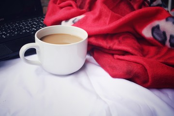 Computer notebook with coffee cup on the bed