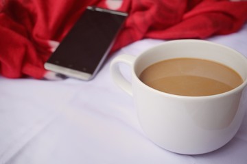 Smart phone with coffee cup on the bed