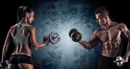 Foto op Canvas Athletic man and woman with a dumbells. © bondarchik