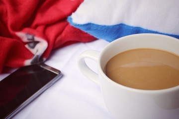 Smart phone with coffee cup on the bed