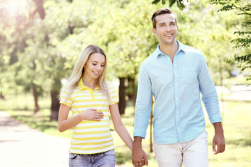 Fototapeta premium Young pregnant woman with husband walking in park