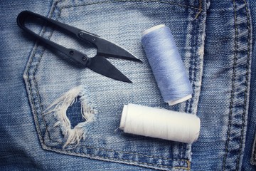 Bobbins threads with scissors on jeans