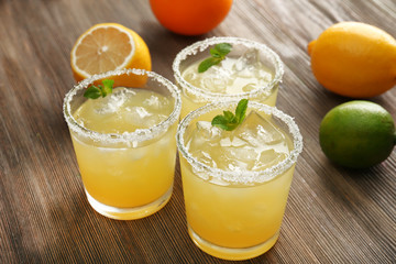 Glasses of lemon juice on wooden table, closeup