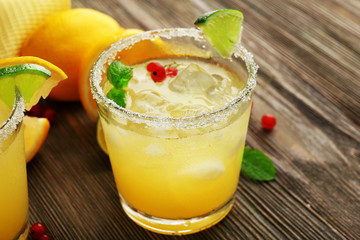 Glass of lemon juice with red currants on wooden table, closeup