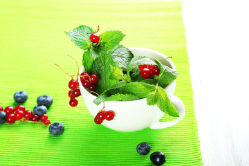 Group of summer berries with mint on green tablecloth background