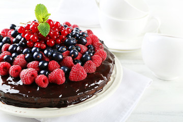Delicious chocolate cake with summer berries on wooden table, closeup