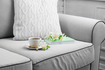 Fototapeta na wymiar Cup of coffee with lump sugar and flowers on sofa