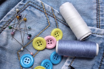 Colorful sewing buttons with thread on jeans