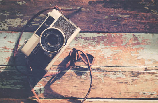 Retro camera on wood table background, vintage color tone , instagram effect filter