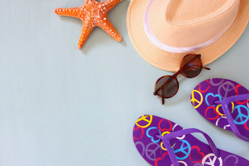 colorful flip flops, starfish, shells, fedora hat and sunglasses on wooden background
