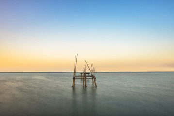 The wooden bamboo in the sea with the sunset light