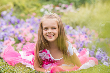 Five-year girl in a beautiful dress in a bed of flowers