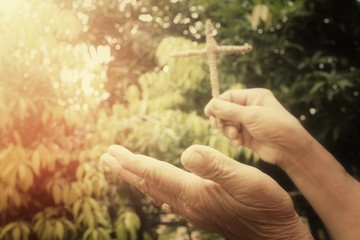 Fototapeta premium Hands praying with cross