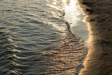 Sea waves with rays of light and sandy beach