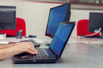 Developer working on source codes on laptop at office.