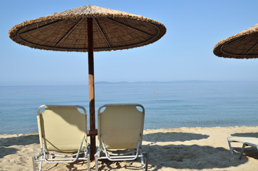 Beach straw parasols and pair of chairs