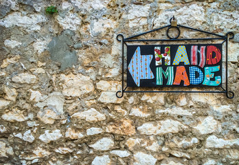 Handmade sign hanging on concrete wall, background.