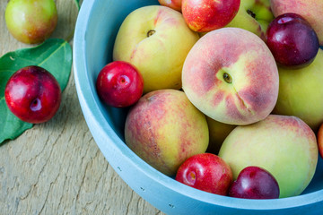 Juicy peaches and apricots in wooden bowl