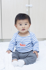 Fototapeta premium Cute Chinese baby boy sitting on a white blanket