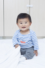 Cute Chinese baby boy sitting on a white blanket