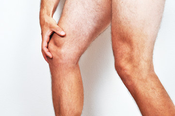 Man holding his knee because of a pain.