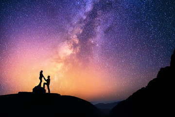 Love is in the air.Romantic couple standing together holding hands in the mountains. Beautiful Milky Way galaxy on the background. - 90230823