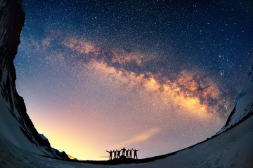 Teamwork and support. A group of people are standing together holding hands against the Milky Way in the mountains.  - 90230833