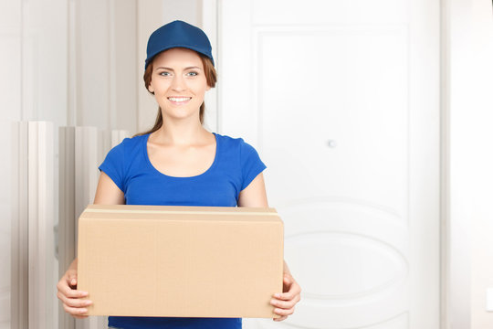 Nice deliverywoman standing near door 
