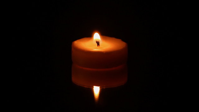Single burning candle in the dark