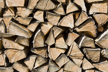 Stos porąbanego drewna na opał.
Tło ze złożonego pod ścianą drewna opałowego.